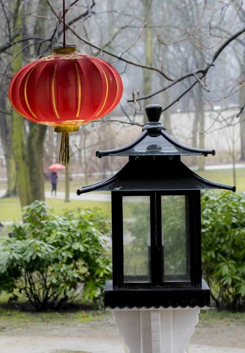 Red paper lantern hanging beside a black garden lamp